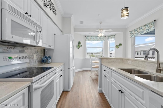 kitchen with decorative light fixtures, sink, white cabinets, ornamental molding, and white appliances