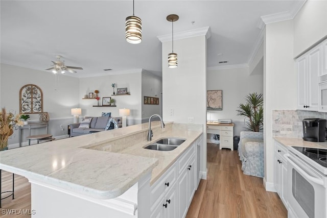 kitchen with sink, white cabinetry, ornamental molding, light stone countertops, and decorative light fixtures