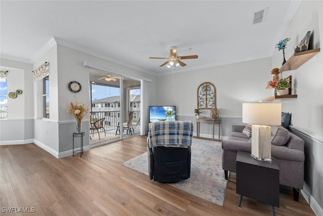 living room featuring ceiling fan, ornamental molding, and wood-type flooring