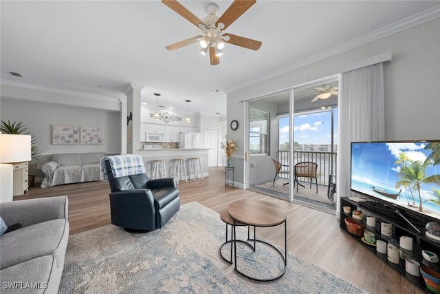 living room with ornamental molding, ceiling fan, and light wood-type flooring