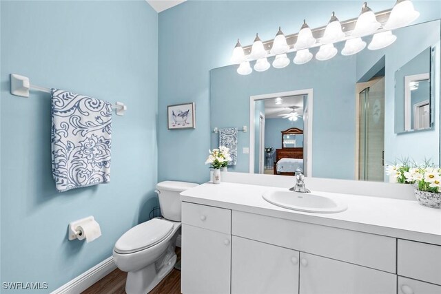 bathroom featuring vanity, hardwood / wood-style floors, a shower with shower door, and toilet