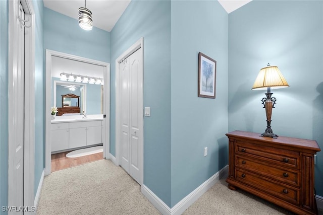 hallway with light carpet and sink