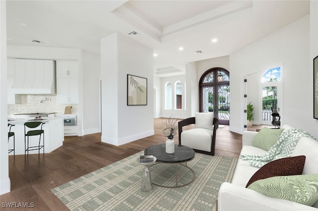 living room featuring a raised ceiling and dark wood-type flooring