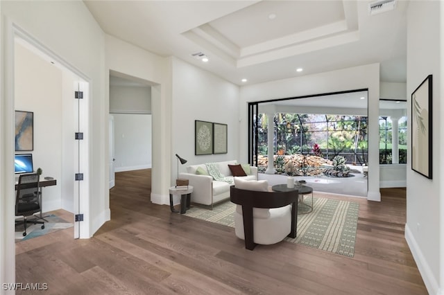 sitting room with wood-type flooring and a raised ceiling