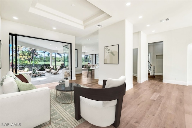 living room featuring light hardwood / wood-style flooring and a raised ceiling