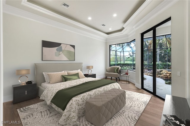 bedroom with a raised ceiling, crown molding, wood-type flooring, and access to exterior