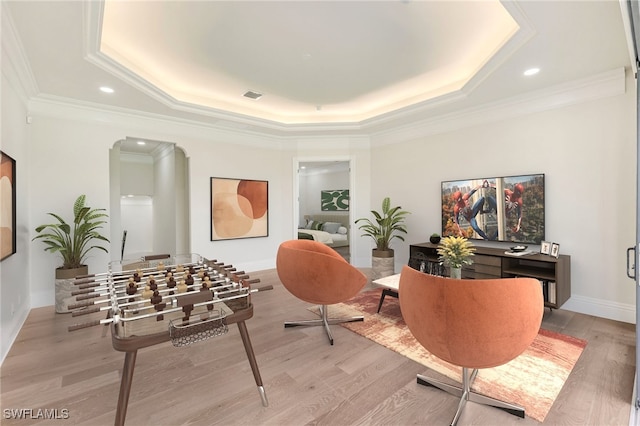 interior space featuring ornamental molding, a raised ceiling, and light hardwood / wood-style flooring