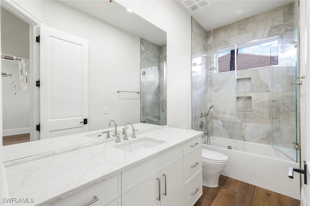 full bathroom featuring vanity, hardwood / wood-style flooring, bath / shower combo with glass door, and toilet