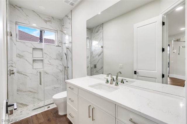 bathroom featuring a shower with door, vanity, hardwood / wood-style floors, and toilet