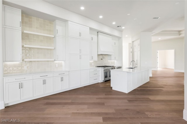 kitchen with double oven range, sink, custom exhaust hood, and white cabinets