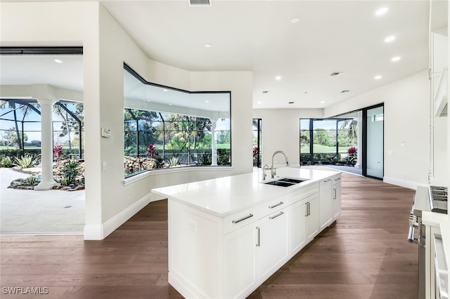 kitchen with a kitchen island with sink, sink, white cabinetry, and dark wood-type flooring