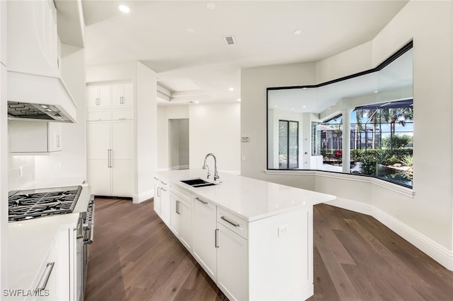 kitchen featuring stainless steel gas cooktop, sink, white cabinetry, an island with sink, and custom range hood