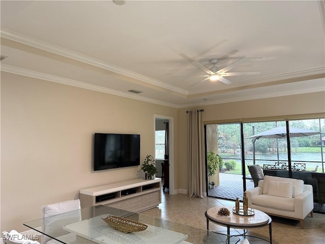 living room with crown molding, ceiling fan, a raised ceiling, and light tile patterned floors