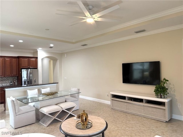 tiled living room featuring a tray ceiling, crown molding, and ceiling fan