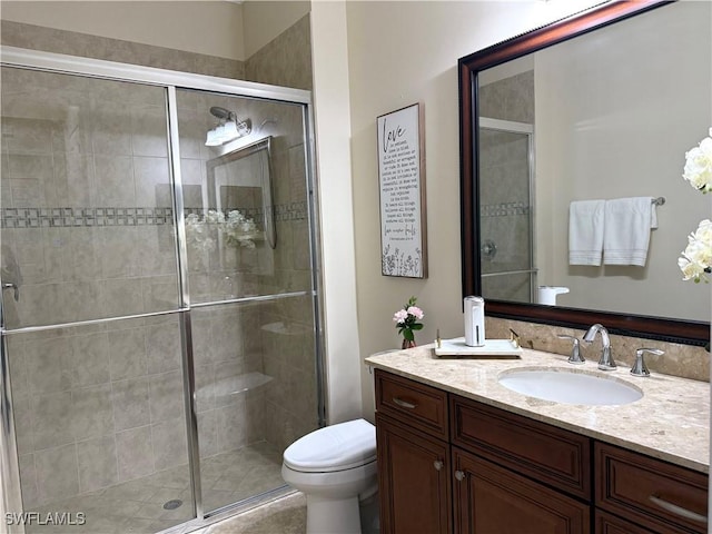 bathroom featuring vanity, toilet, and a shower with door