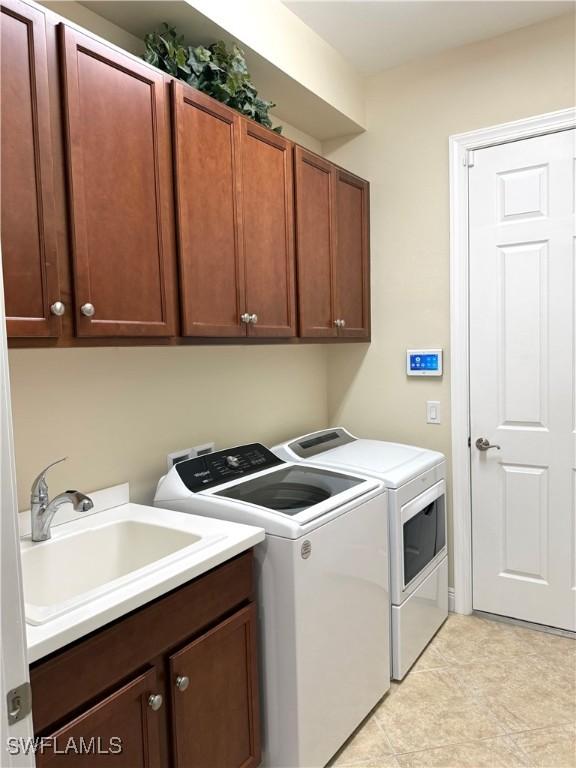 clothes washing area with cabinets, sink, and washing machine and dryer