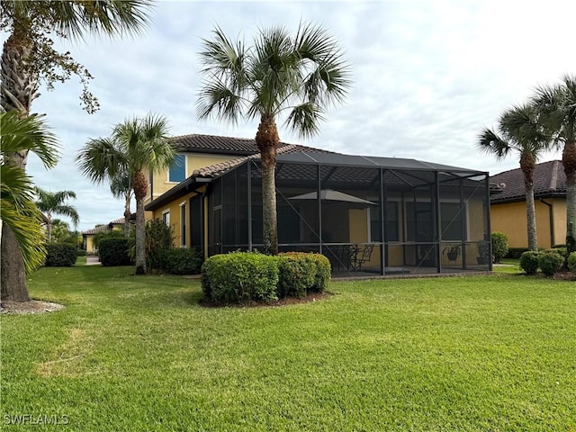 back of property featuring a lawn and glass enclosure