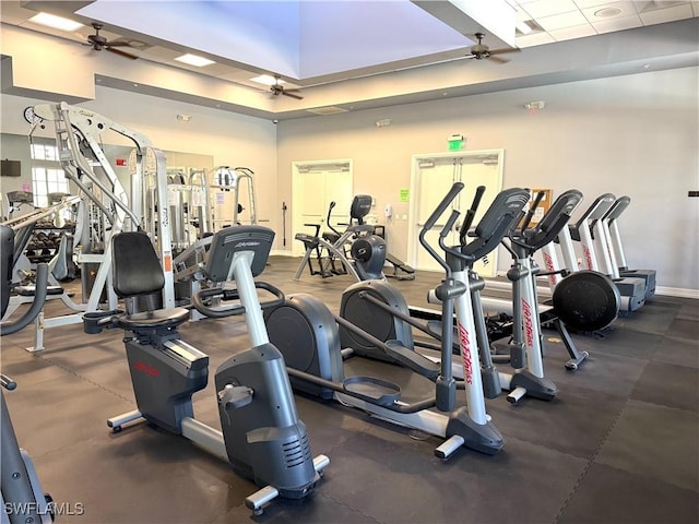 workout area with ceiling fan, a skylight, and a high ceiling