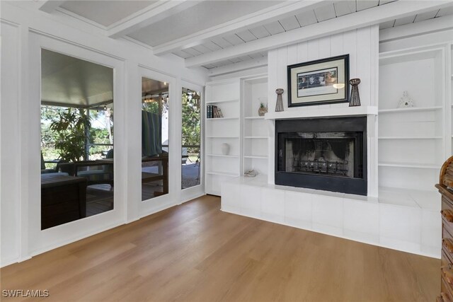 unfurnished living room with built in shelves, wood-type flooring, and beamed ceiling