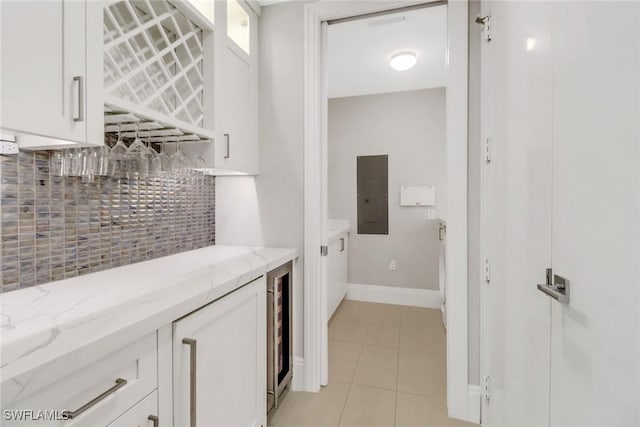 interior space with white cabinetry, decorative backsplash, light tile patterned floors, electric panel, and light stone counters