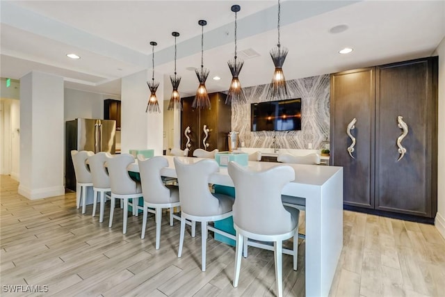 bar with pendant lighting, high quality fridge, dark brown cabinets, and light wood-type flooring