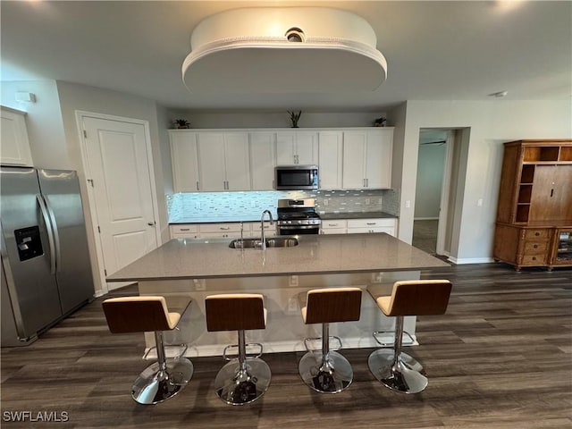 kitchen featuring sink, appliances with stainless steel finishes, light stone counters, an island with sink, and white cabinets