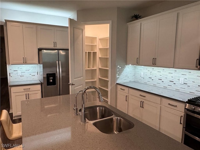 kitchen with tasteful backsplash, appliances with stainless steel finishes, sink, and dark stone countertops