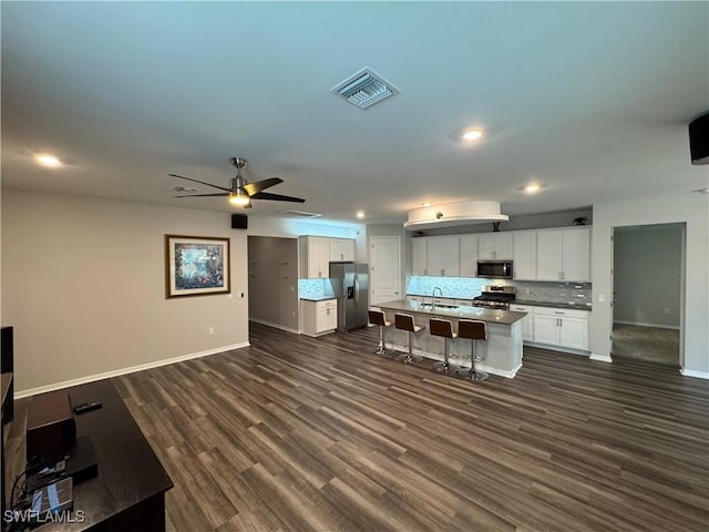 kitchen with a kitchen bar, sink, stainless steel appliances, a kitchen island with sink, and white cabinets