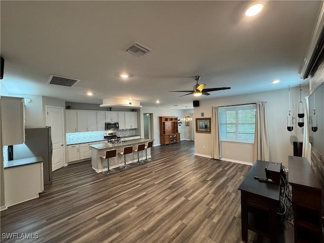 kitchen with dark hardwood / wood-style floors, tasteful backsplash, white cabinets, ceiling fan, and stainless steel appliances