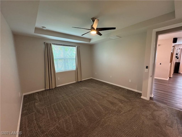 carpeted empty room with ceiling fan and a raised ceiling