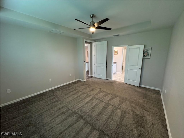 unfurnished bedroom with ceiling fan and dark colored carpet