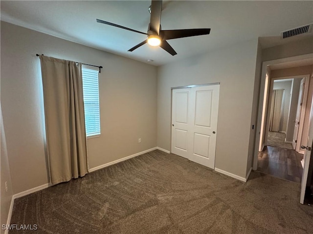 unfurnished bedroom featuring ceiling fan, dark carpet, and a closet