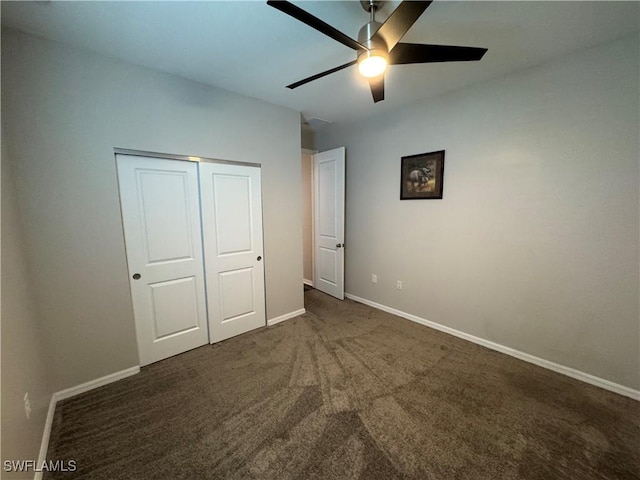 unfurnished bedroom with ceiling fan, a closet, and dark colored carpet