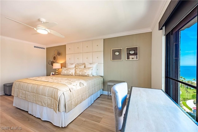 bedroom with ornamental molding, a water view, light wood finished floors, and a ceiling fan