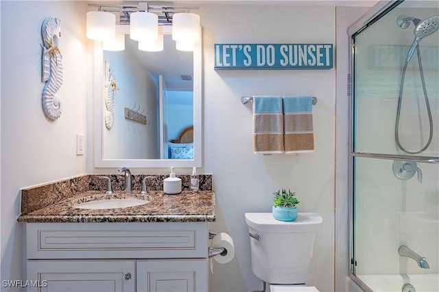 bathroom featuring vanity, toilet, and bath / shower combo with glass door