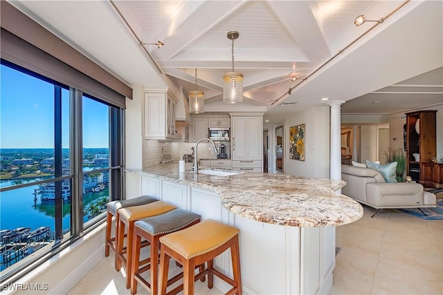 kitchen featuring stainless steel microwave, a breakfast bar, open floor plan, decorative light fixtures, and a sink