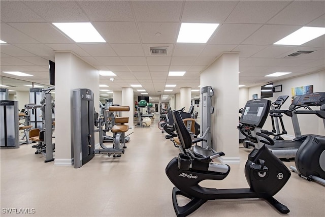 exercise room with a paneled ceiling, baseboards, and visible vents