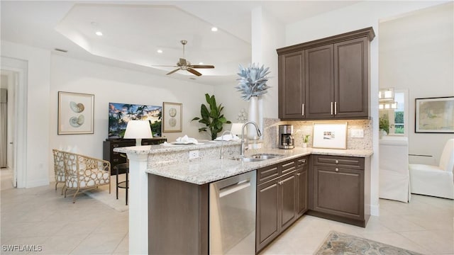 kitchen with sink, backsplash, light stone countertops, stainless steel dishwasher, and kitchen peninsula