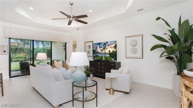 living room featuring a tray ceiling and ceiling fan