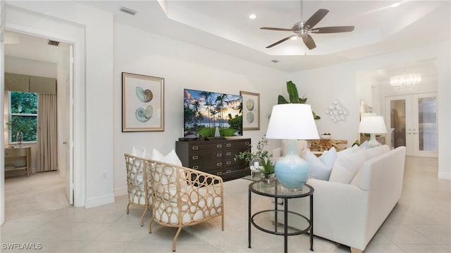 tiled living room featuring french doors, ceiling fan, and a tray ceiling