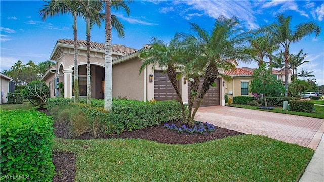 mediterranean / spanish house with a garage and a front lawn