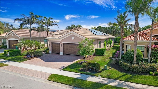 mediterranean / spanish home with a garage, a front lawn, and solar panels