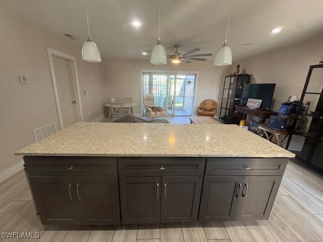 kitchen featuring hanging light fixtures, light stone countertops, and ceiling fan