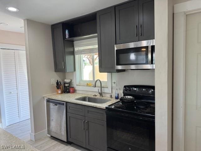 kitchen with appliances with stainless steel finishes, sink, and light hardwood / wood-style flooring