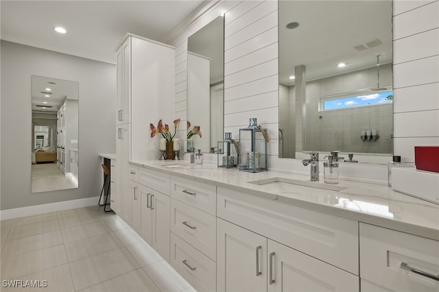 bathroom with a tile shower, vanity, and tile patterned flooring