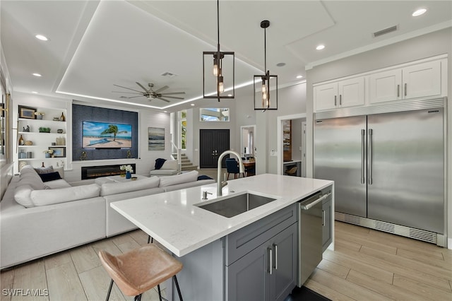 kitchen featuring sink, a center island with sink, hanging light fixtures, and appliances with stainless steel finishes