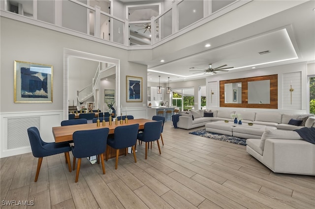 dining area featuring ceiling fan, light hardwood / wood-style floors, and a high ceiling