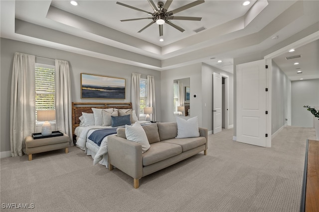 carpeted bedroom with multiple windows and a raised ceiling