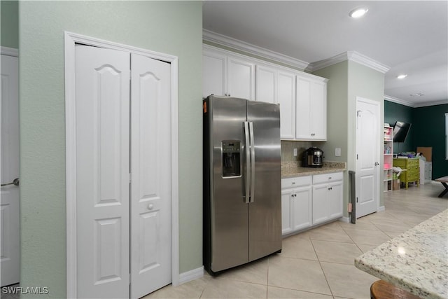 kitchen featuring crown molding, tasteful backsplash, light stone counters, stainless steel fridge, and white cabinets