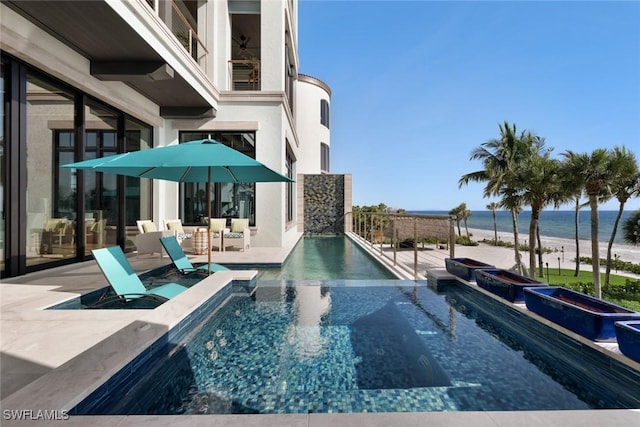 view of pool with a view of the beach, a jacuzzi, a patio, and a water view